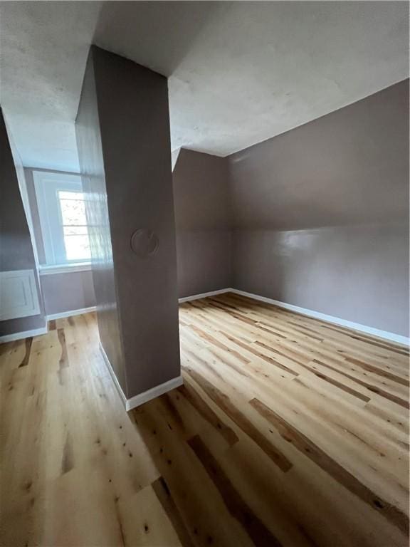 additional living space featuring hardwood / wood-style flooring and vaulted ceiling