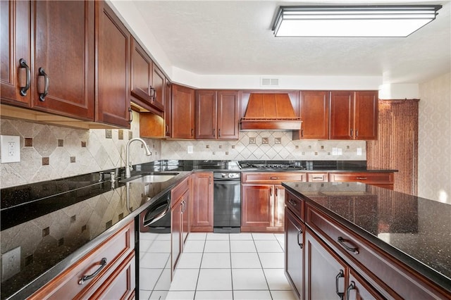 kitchen featuring premium range hood, sink, dark stone countertops, dishwashing machine, and stainless steel gas cooktop