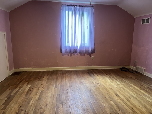 additional living space with vaulted ceiling and wood-type flooring