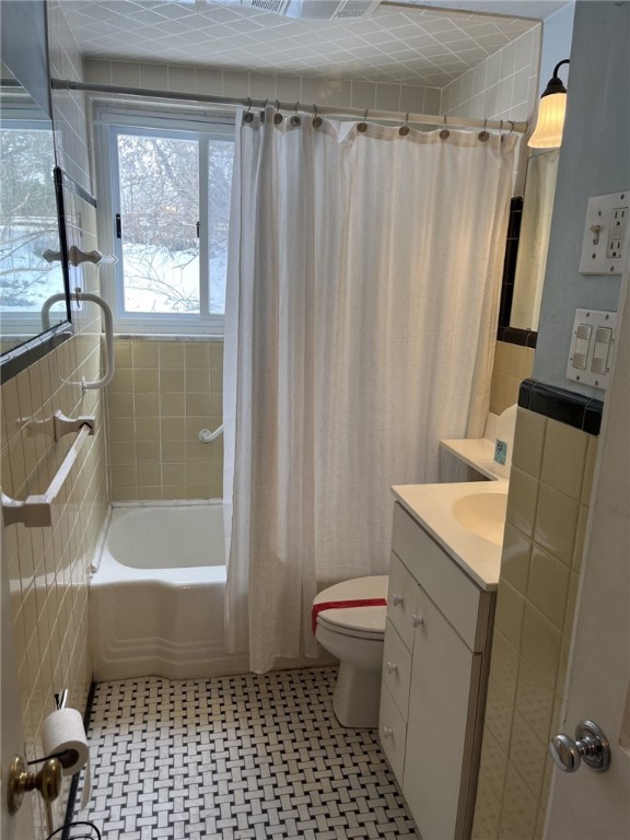 full bathroom featuring vanity, toilet, shower / tub combo, and tile walls