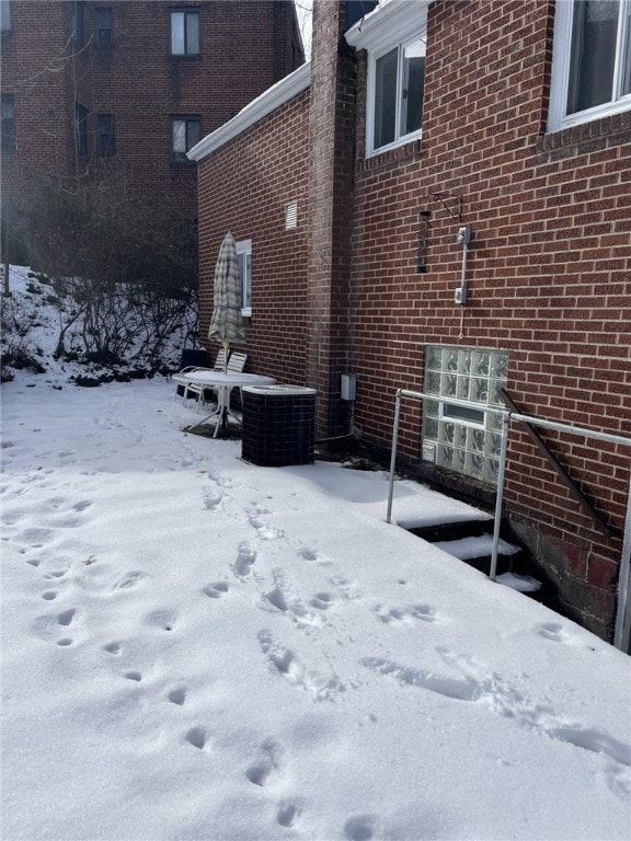 view of snow covered exterior featuring central AC unit