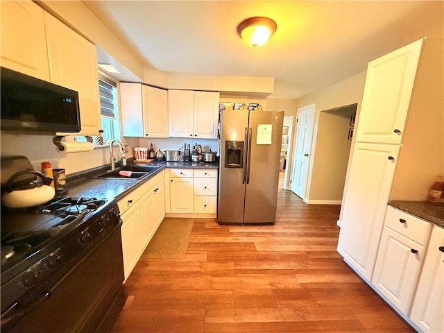 kitchen featuring white cabinetry, light hardwood / wood-style floors, sink, and black appliances