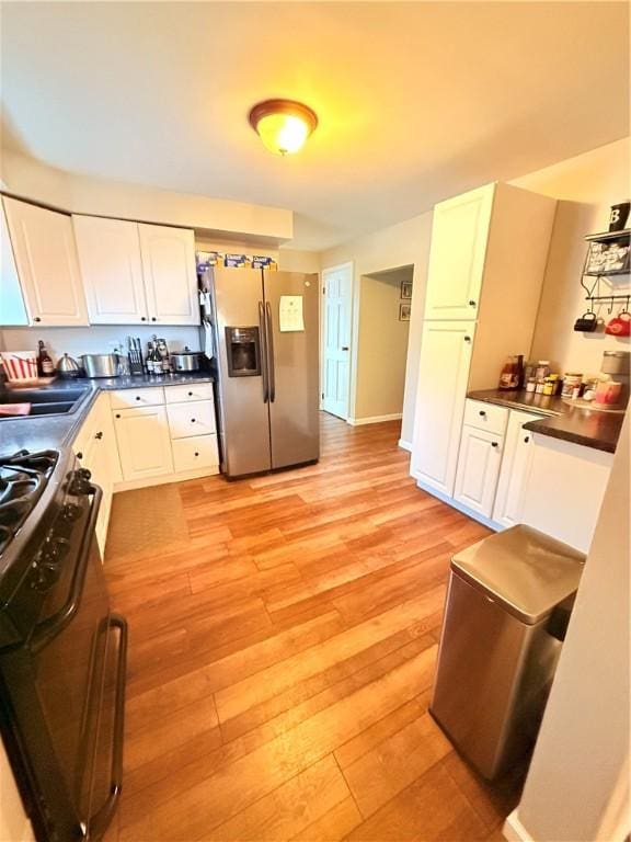 kitchen featuring white cabinetry, black gas range oven, light hardwood / wood-style flooring, and stainless steel refrigerator with ice dispenser