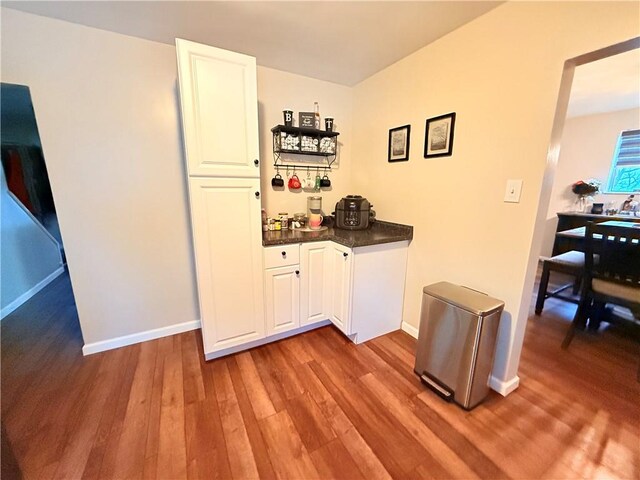 bar featuring light hardwood / wood-style floors and white cabinets