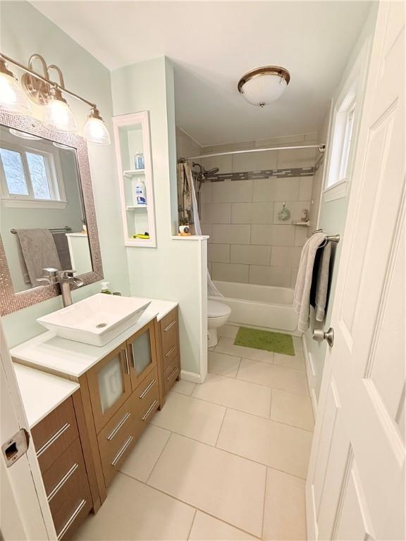 full bathroom featuring tile patterned flooring, tiled shower / bath, a wealth of natural light, and vanity