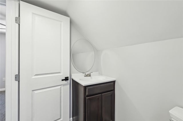 bathroom featuring vanity, vaulted ceiling, and toilet