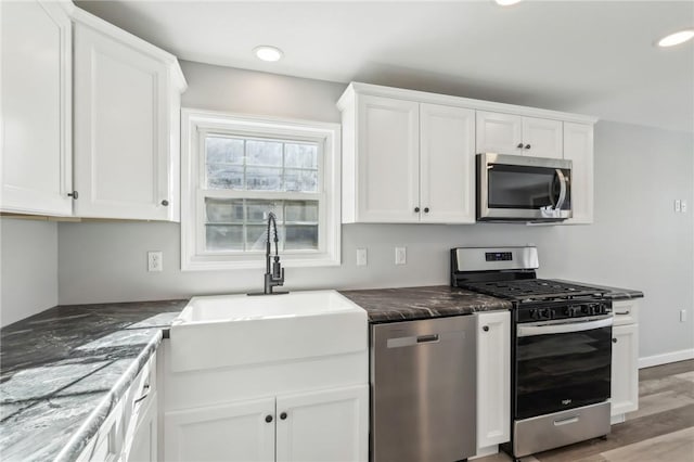 kitchen with white cabinetry, appliances with stainless steel finishes, sink, and wood-type flooring