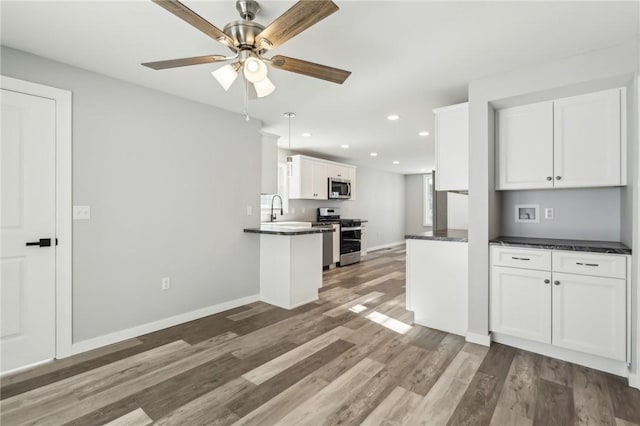 kitchen featuring pendant lighting, sink, appliances with stainless steel finishes, white cabinets, and kitchen peninsula