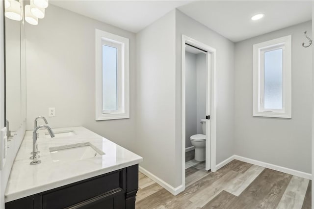 bathroom featuring vanity, hardwood / wood-style flooring, a chandelier, and toilet