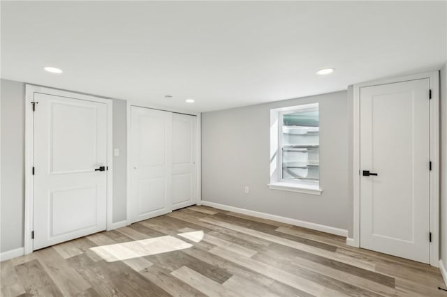 unfurnished bedroom with two closets and light hardwood / wood-style floors