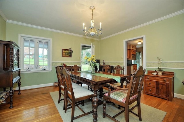 dining area with baseboards, a notable chandelier, wood finished floors, and crown molding