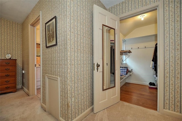 hall featuring wallpapered walls, baseboards, and light carpet