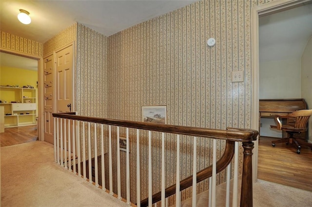 corridor featuring an upstairs landing, carpet, wood finished floors, and wallpapered walls