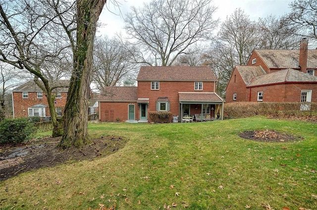 back of property featuring a yard and brick siding