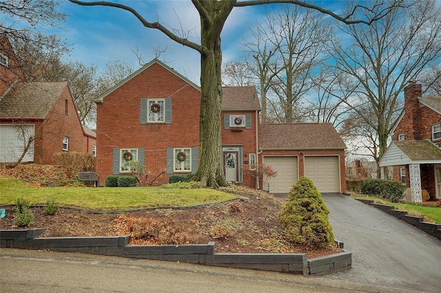 view of front of house with aphalt driveway, an attached garage, brick siding, and a front yard