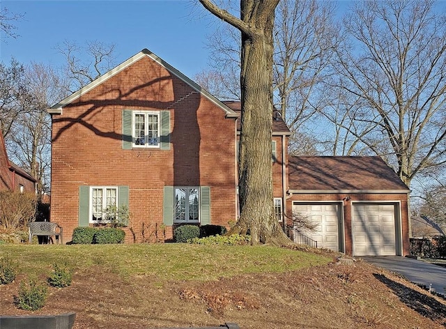 view of front of property with aphalt driveway, brick siding, a garage, and a front lawn