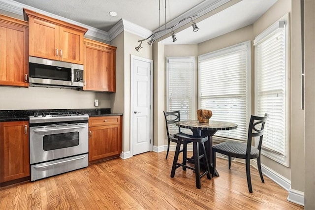 kitchen with crown molding, appliances with stainless steel finishes, light hardwood / wood-style floors, and a wealth of natural light