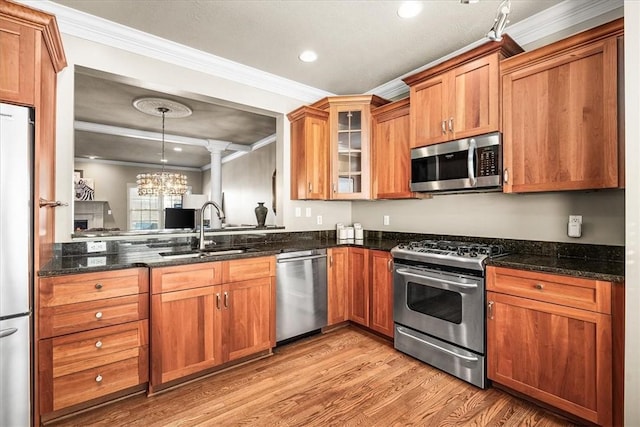 kitchen featuring hanging light fixtures, crown molding, appliances with stainless steel finishes, and sink