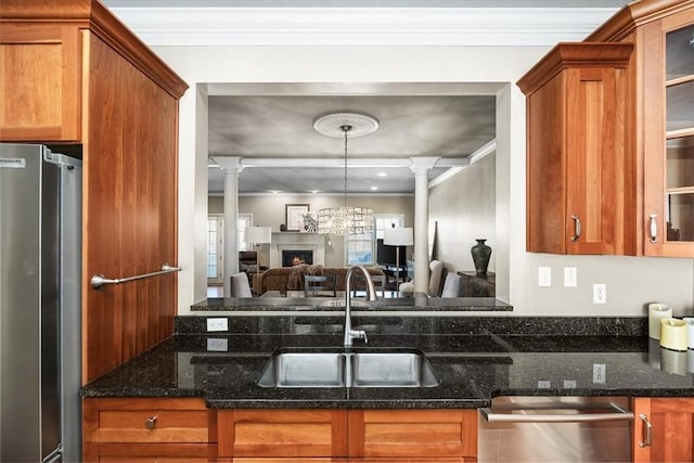 kitchen with ornate columns, appliances with stainless steel finishes, sink, and dark stone countertops