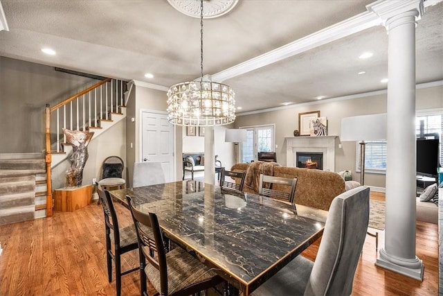 dining area featuring decorative columns, ornamental molding, a healthy amount of sunlight, and hardwood / wood-style floors