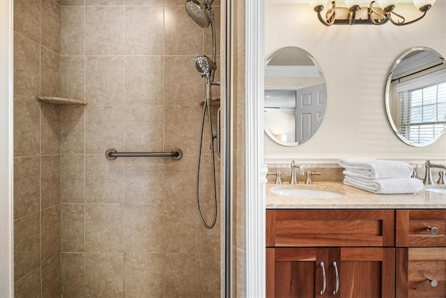 bathroom with tiled shower, vanity, and ornamental molding