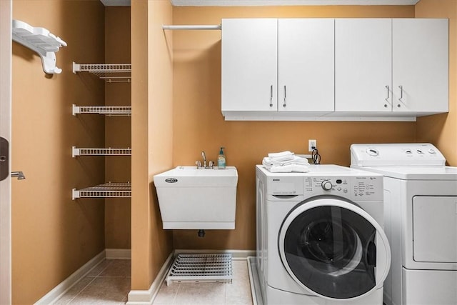 laundry room featuring cabinets, light tile patterned flooring, separate washer and dryer, and sink