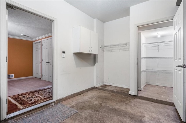 clothes washing area with crown molding and a textured ceiling