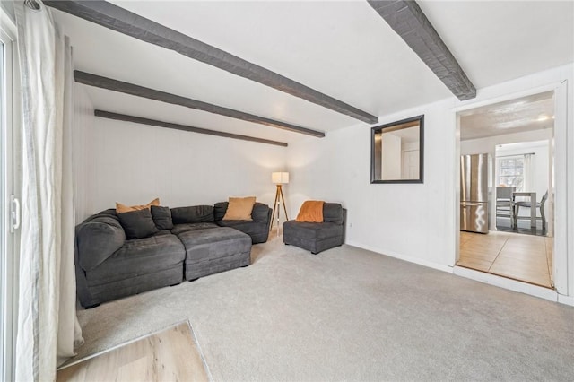 carpeted living room with beamed ceiling