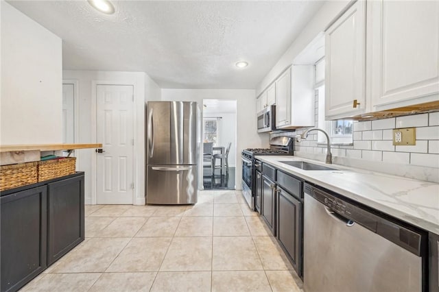 kitchen featuring sink, light stone counters, a textured ceiling, appliances with stainless steel finishes, and white cabinets