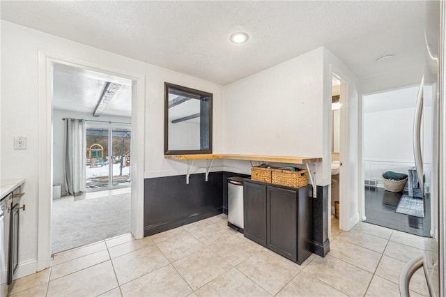 kitchen with light colored carpet, a textured ceiling, and stainless steel appliances