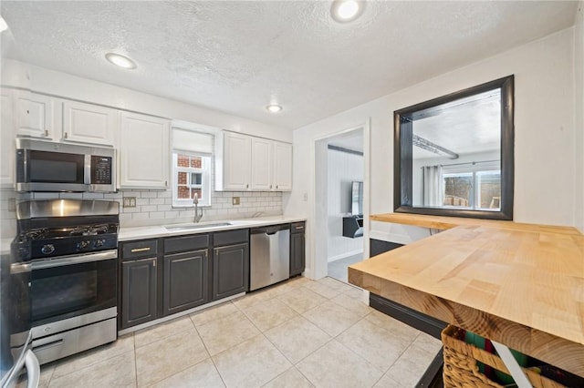 kitchen with tasteful backsplash, stainless steel appliances, sink, and white cabinets