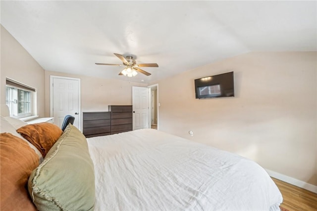 bedroom with hardwood / wood-style flooring, vaulted ceiling, and ceiling fan