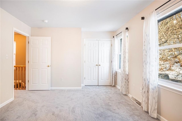 unfurnished bedroom with light carpet and a closet