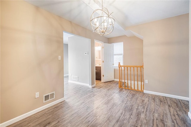 empty room featuring wood-type flooring and a chandelier