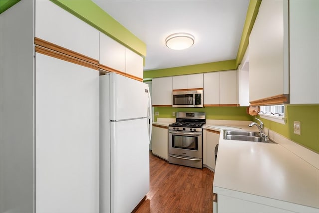 kitchen with white cabinetry, appliances with stainless steel finishes, sink, and wood-type flooring