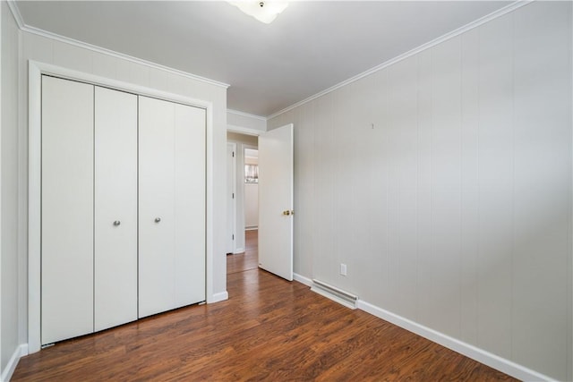 unfurnished bedroom featuring dark wood-type flooring, ornamental molding, and a closet