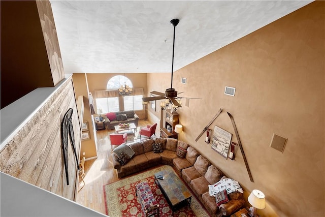 living room with a towering ceiling and ceiling fan with notable chandelier