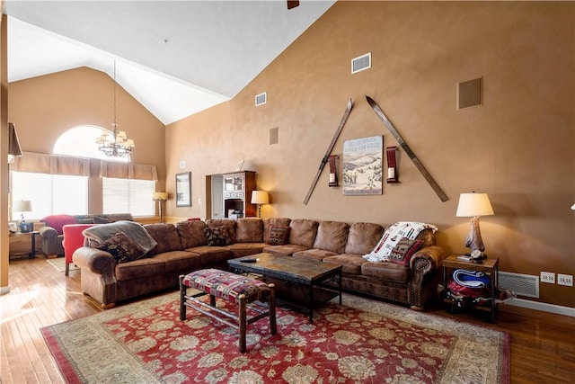 living room with hardwood / wood-style flooring, high vaulted ceiling, and a chandelier