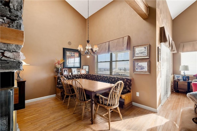 dining space with light hardwood / wood-style flooring, high vaulted ceiling, and a chandelier