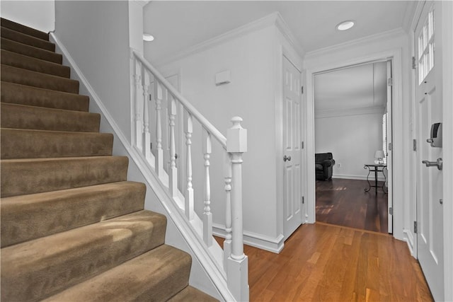 stairs with hardwood / wood-style flooring and ornamental molding