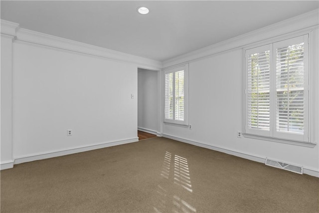 empty room featuring crown molding and dark colored carpet