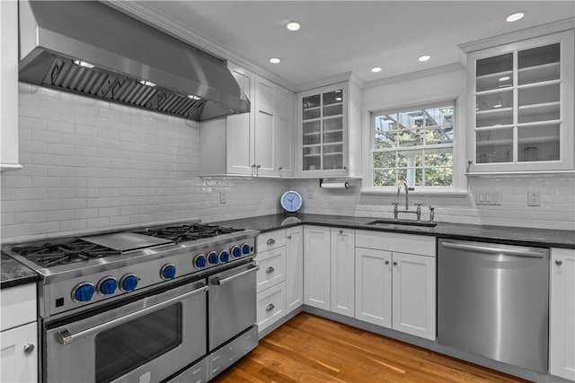 kitchen with wall chimney range hood, sink, white cabinets, and appliances with stainless steel finishes