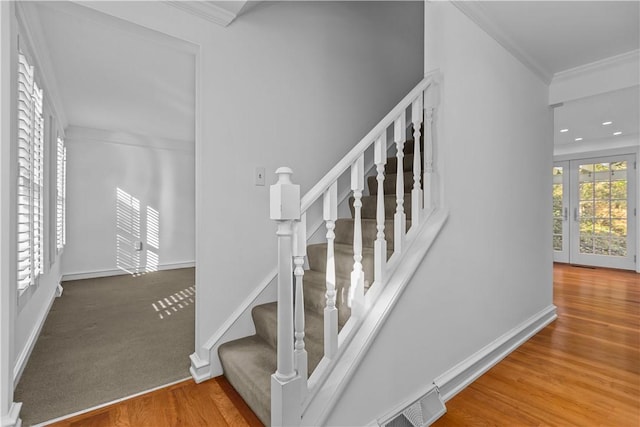 staircase featuring ornamental molding, wood-type flooring, and french doors