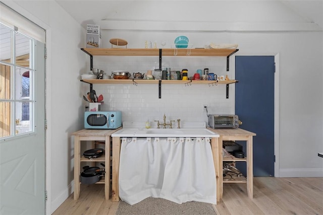 bar featuring sink, light hardwood / wood-style flooring, and backsplash