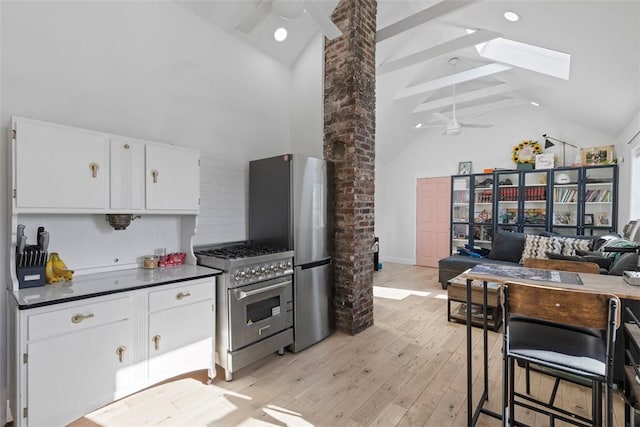 kitchen with white cabinetry, a skylight, light hardwood / wood-style flooring, appliances with stainless steel finishes, and ceiling fan