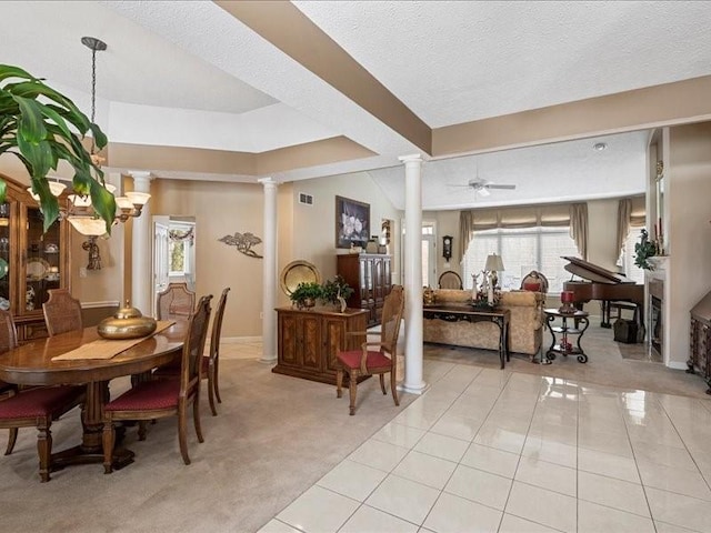 dining area with ceiling fan, light tile patterned floors, a textured ceiling, and ornate columns