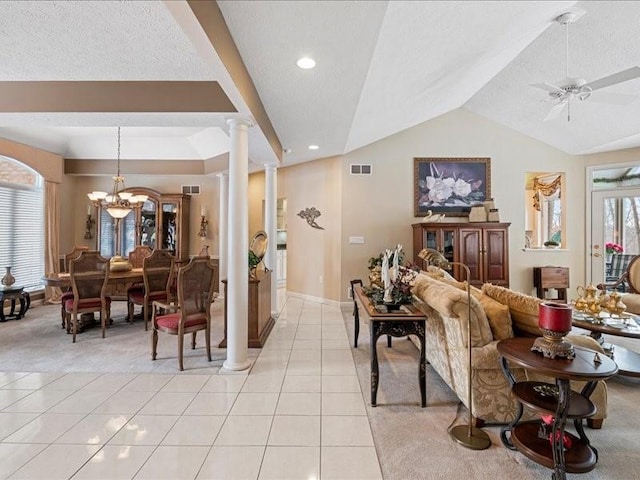 living room with light tile patterned floors, a textured ceiling, ceiling fan with notable chandelier, vaulted ceiling, and ornate columns