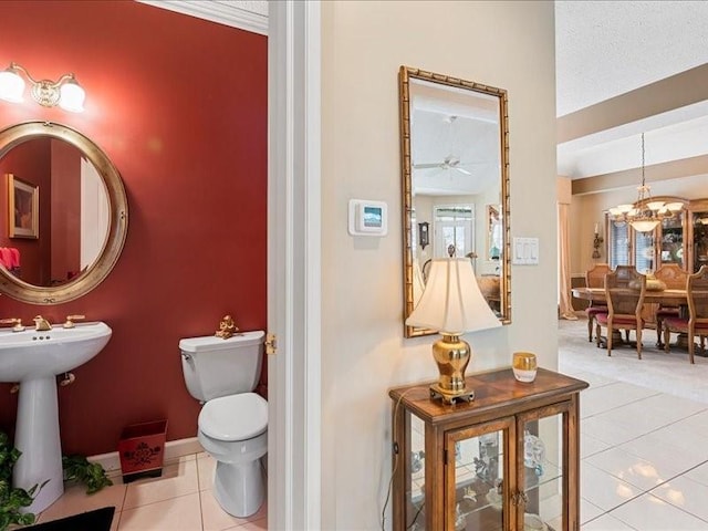 bathroom featuring tile patterned flooring, sink, ceiling fan with notable chandelier, and toilet