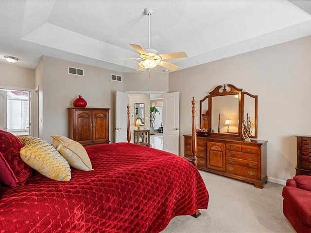 carpeted bedroom with ceiling fan and a tray ceiling