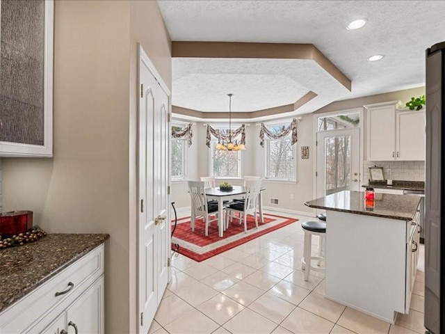 kitchen featuring white cabinetry, tasteful backsplash, a center island, a textured ceiling, and a tray ceiling